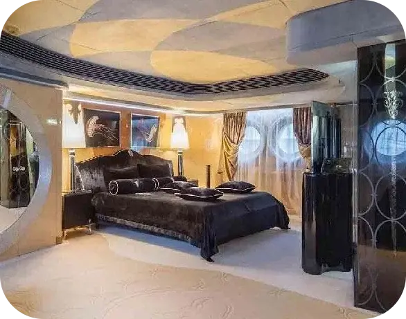 Big Boaty cabin with a black velvet bed and bolster cushions, jellyfish artworks on gold-toned walls and two curtained portholes