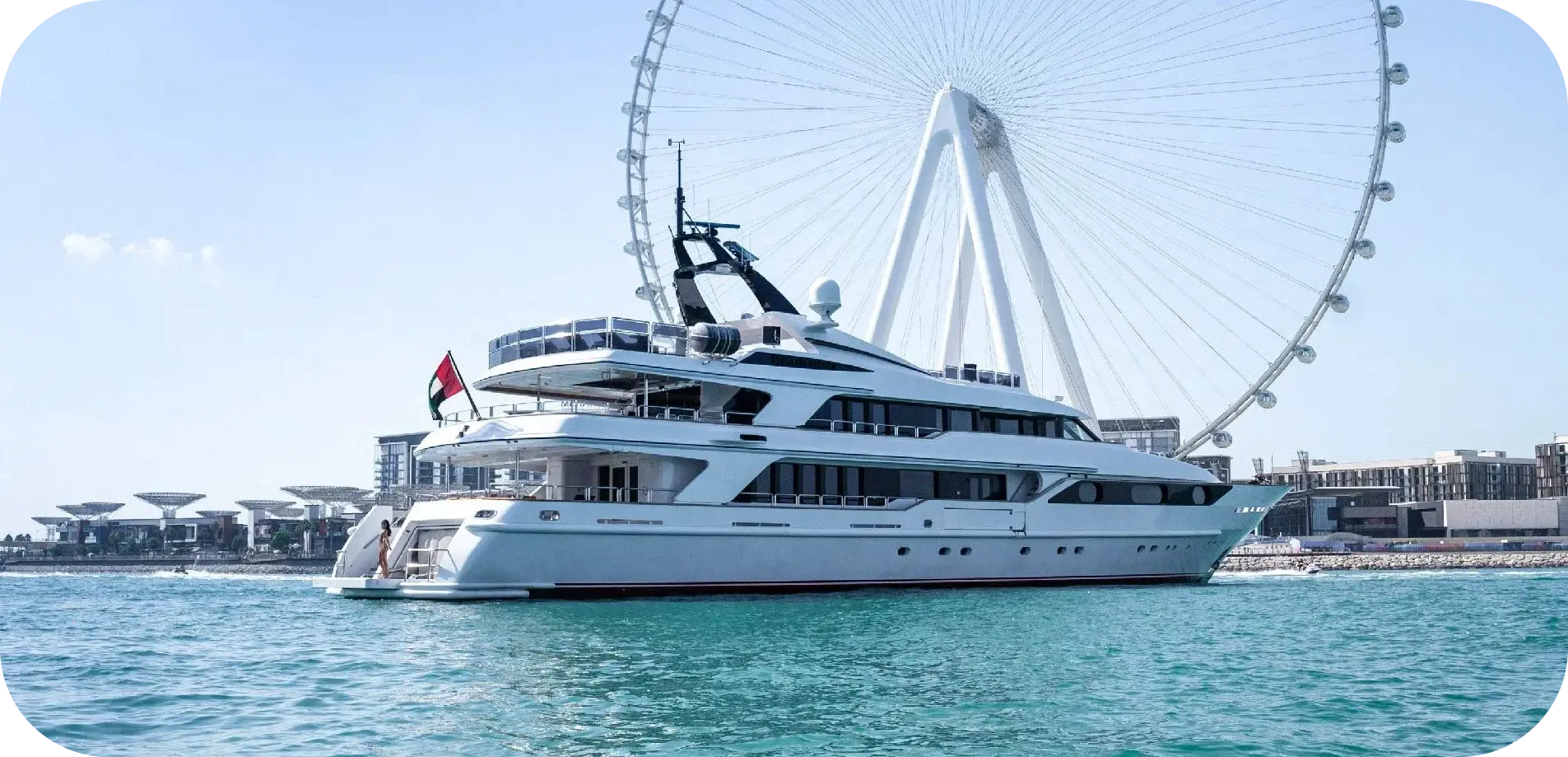 Side view of Big Daddy, a white 165 ft Benetti with stacked decks and a dark radar arch, off Bluewaters in Dubai with Ain Dubai behind