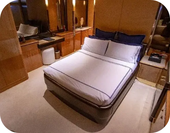 Big Daddy guest cabin with a double bed in white linen, navy cushions, pale wood panelling and a vanity mirror