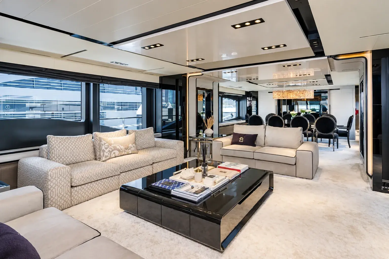 Illustration of the Bridgetown main saloon, with cream sofas around a black lacquer coffee table and the dining table and a crystal chandelier beyond