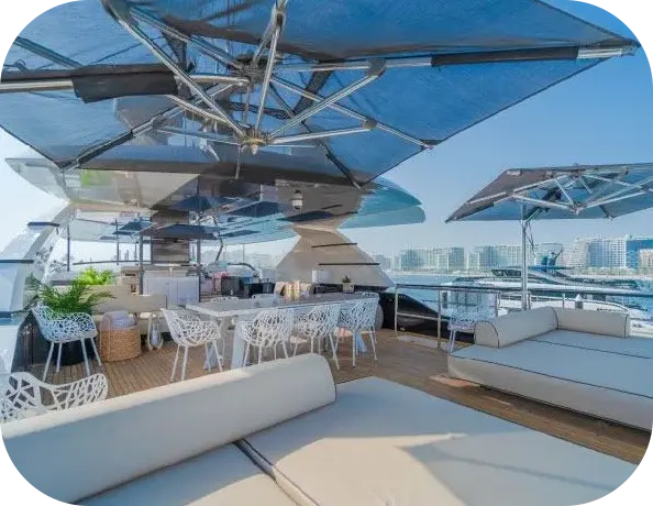 Bridgetown upper deck with a long dining table, white lattice chairs, cushioned sunbeds and large square parasols