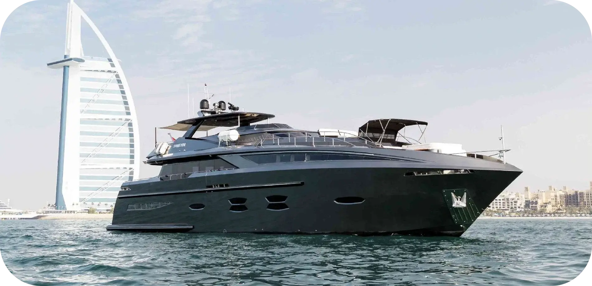 Side view of Eclipse, a near-black 115 ft Logos Marine yacht with a flybridge hardtop, off the Dubai coast near the Burj Al Arab