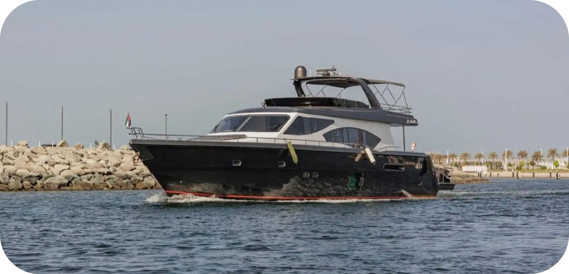 Side view of Grey Beast under way, showing the black hull, red boot stripe, grey deckhouse and flybridge hardtop