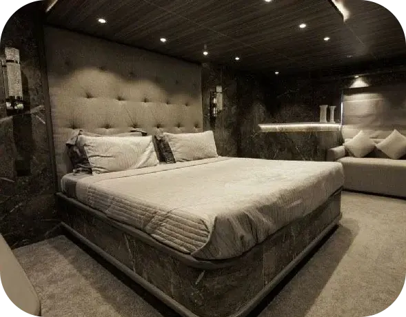 Grey Beast guest cabin with a double bed, a tall tufted headboard, dark marble walls and a sofa under a timber ceiling