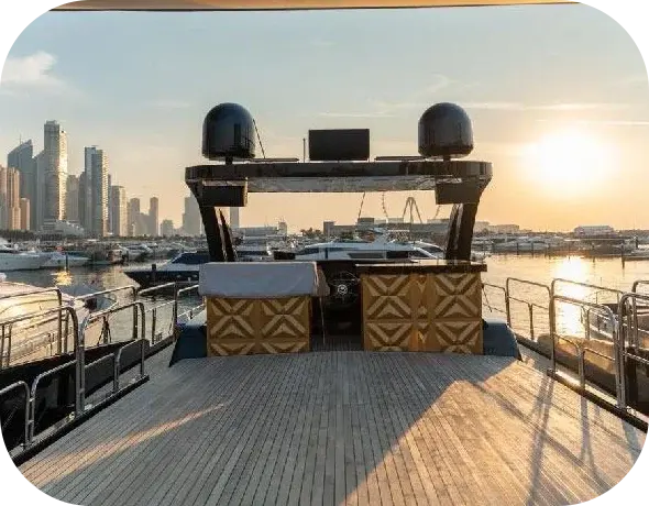 The open teak flybridge of I Don't Know at sunset, with the upper helm, gold-patterned consoles and a black radar arch