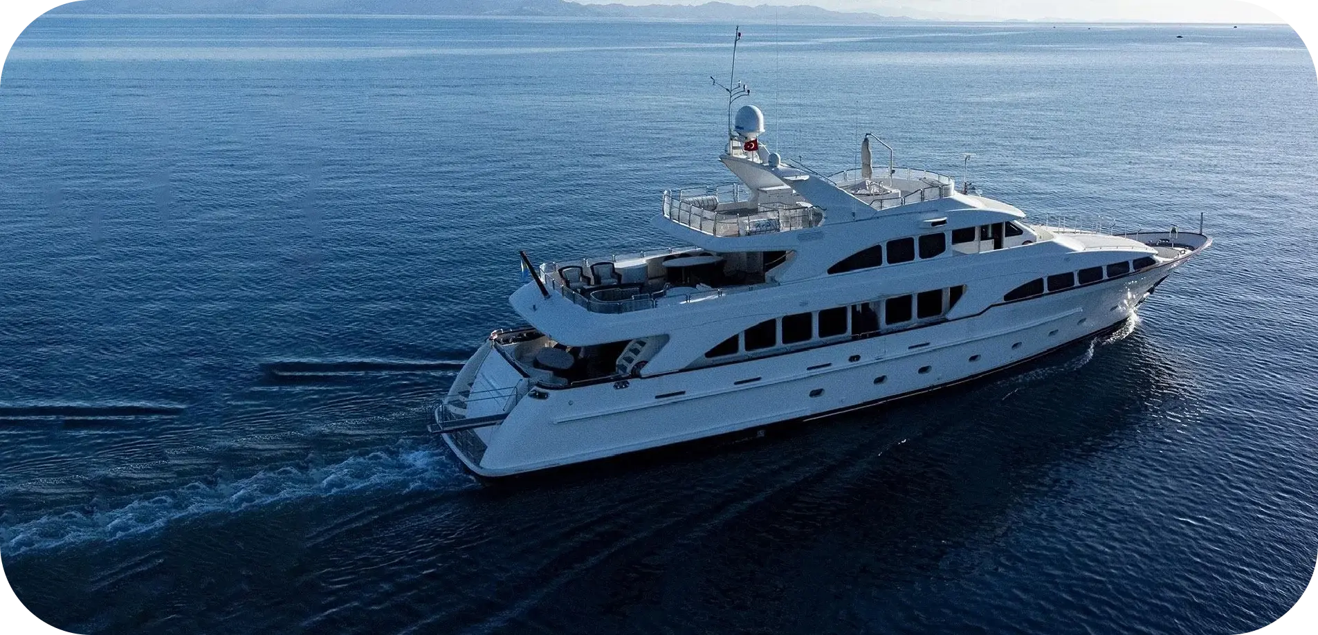 Side view of Island Girl 2, a white Benetti with three decks and dark tinted windows, cruising on open water
