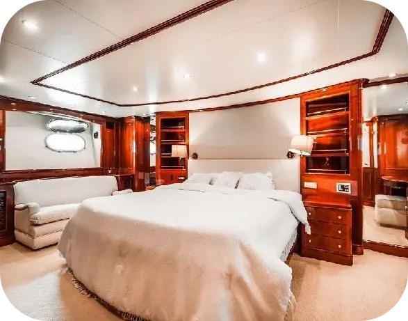 A cabin on Island Girl 2 with a double bed in white linen, timber shelves and a cream sofa beneath two oval portholes