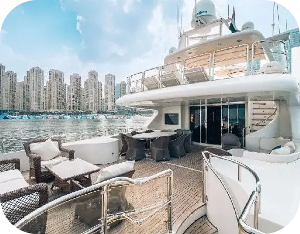 Island Girl 2 aft deck with a round dining table, wicker armchairs and white sofas on teak, with city towers across the water