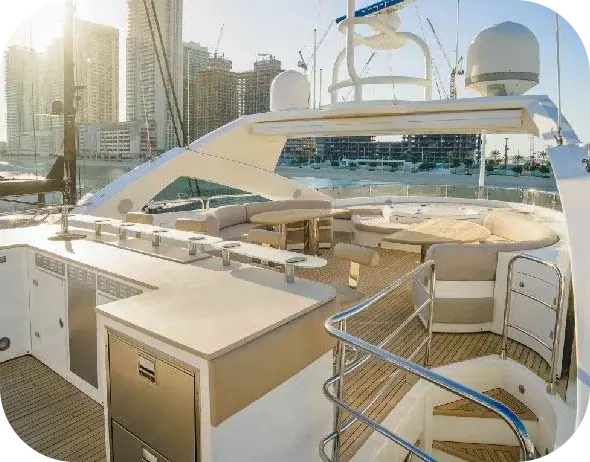 Liquid Asset sundeck with a bar counter, a timber dining table and wraparound sofas under the hardtop, with marina towers behind