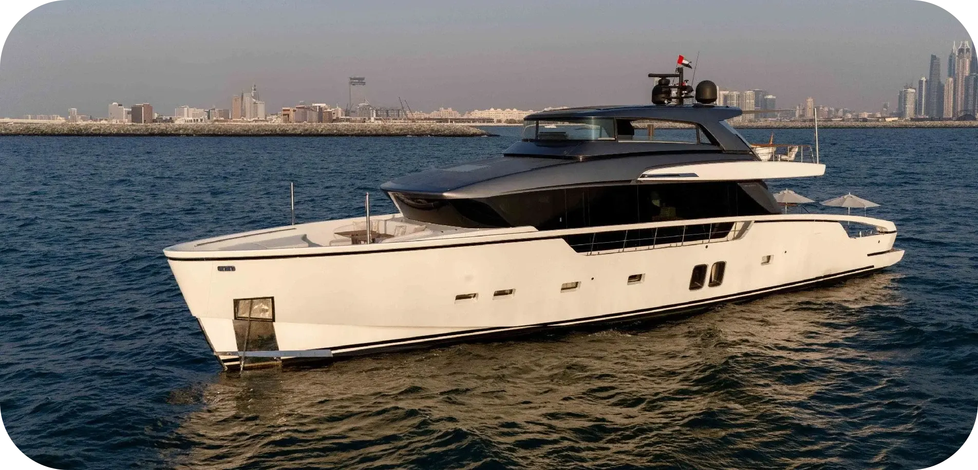 Side view of Lorenzo, a white Sanlorenzo SX88 with a dark superstructure, cruising off the Dubai skyline
