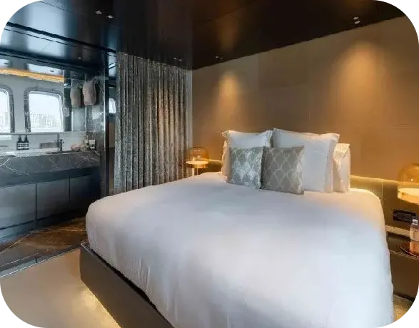 Lorenzo guest cabin with a double bed, bronze lamps and a dark marble bathroom behind a curtain