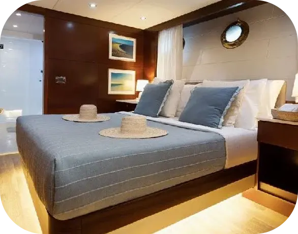 Melody 2 guest cabin with a double bed in blue-striped linen, dark wood panelling, framed sea prints and an en-suite bathroom