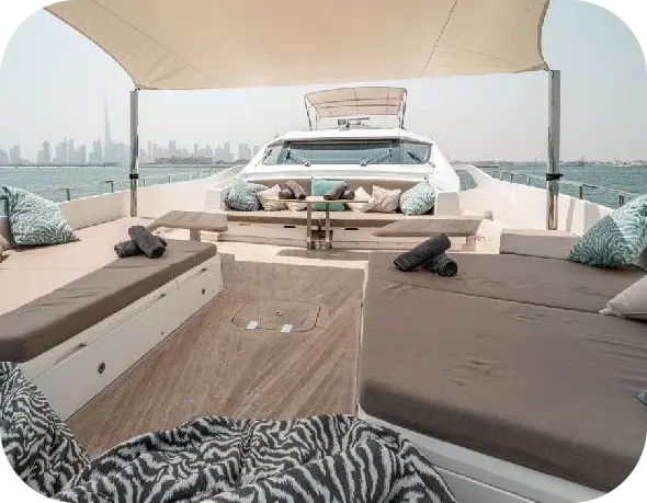 Out of Office bow lounge with grey sunpads, a cushioned sofa against the windscreen and a canvas shade sail, a city skyline behind