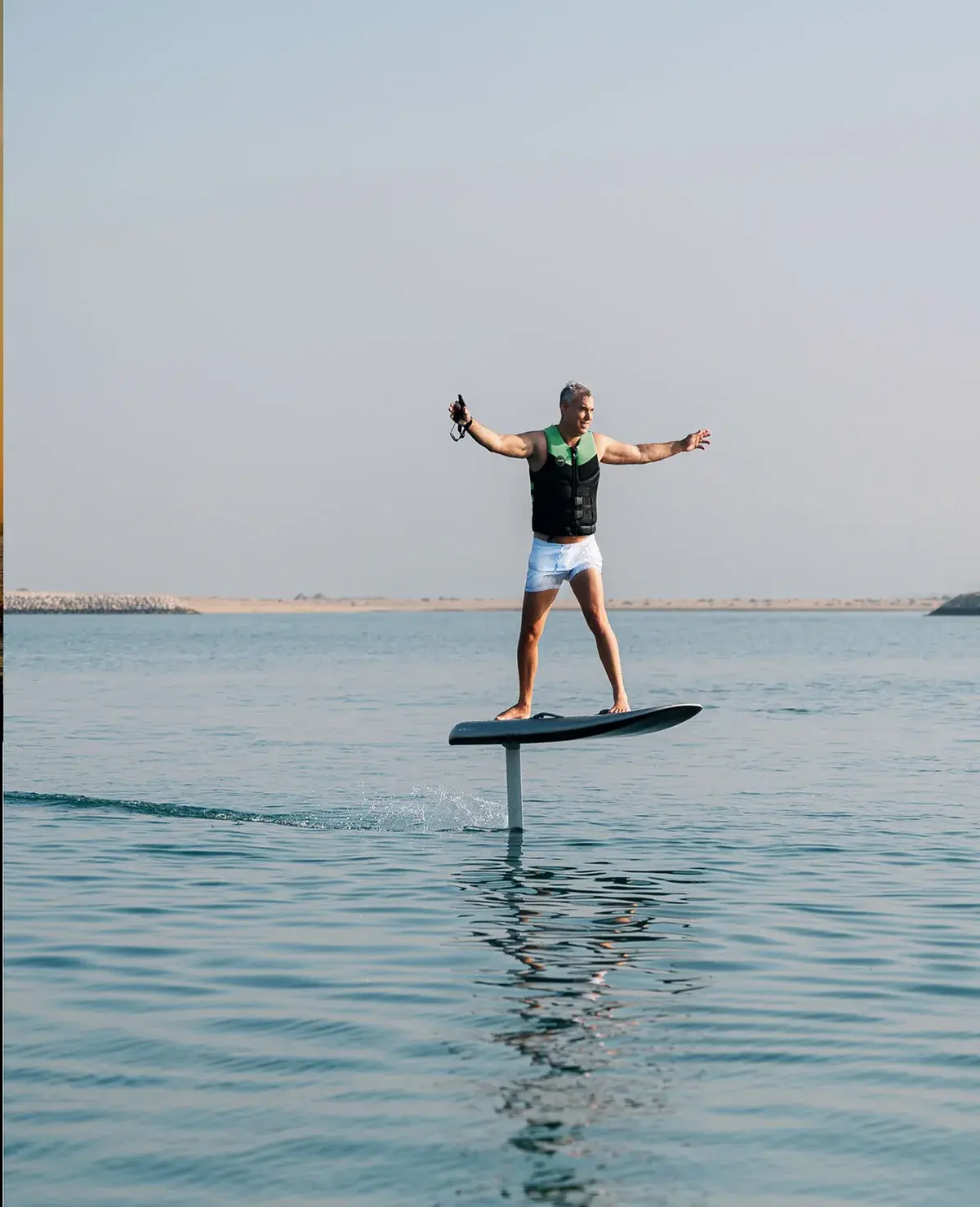 A rider on an electric Flite hydrofoil board above calm water